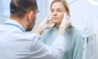 plastic surgeon examines a woman's face